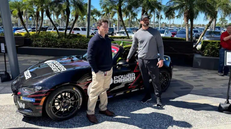 A driver and fan standing next to a car